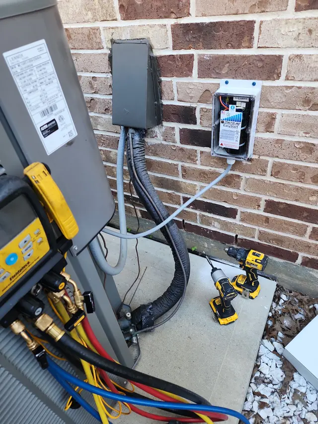 Refrigerant gauges on the line set of a Lennox condenser with a soft start module wired to the wall